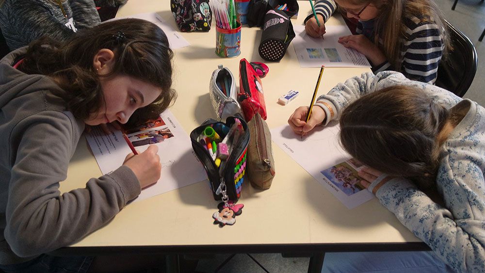 workshop with children drawing a video game with colored pencils